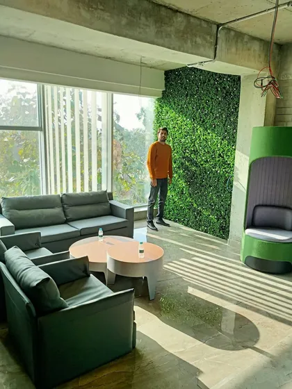 An artificial green wall serves as a feature in this modern office lounge, providing a calming natural backdrop for employees and visitors.