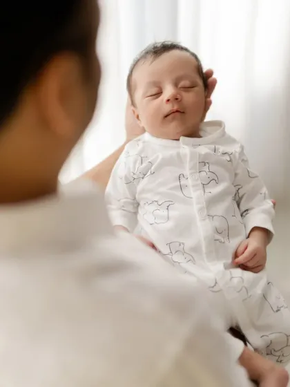 An over the shoulder shot of a father holding his sleeping newborn. This perspective creates a sense of safety and protection.