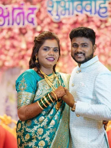 The happy couple posing for a photo at their wedding reception. Her traditional Maharashtrian look was completed with a half-up hairstyle.