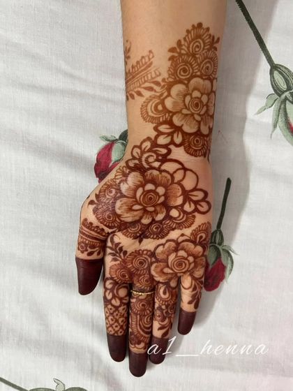 A single hand showing off the beautiful, mature stain of a floral henna design.