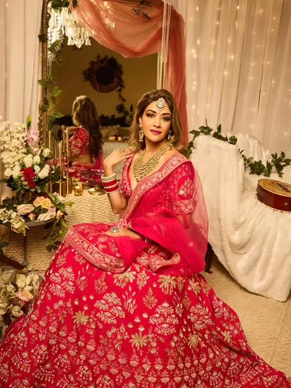 Full Hollywood glam for this bride. The look features voluminous side-swept waves, a smokey eye, and a vibrant pink lehenga, creating a stunning and memorable style for any wedding event.