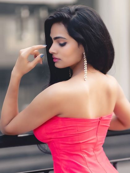 A classic beauty shot from the back. The focus is on her elegant posture, glowing skin, and the stunning drop earrings.