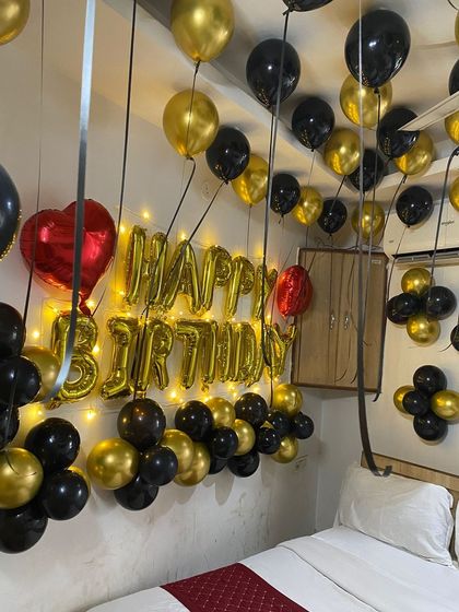 A close-up of the illuminated "Happy Birthday" sign and the surrounding black and gold balloon arrangement.