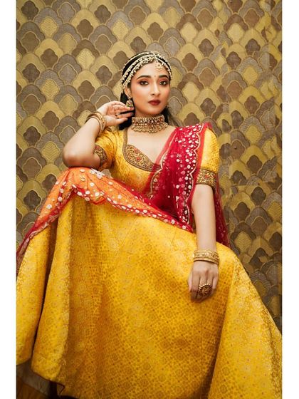 A full view of a model in a yellow lehenga, adorned with our choker set. This shows how our traditional pieces can also be styled with lehengas.