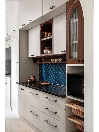 To brighten this kitchen, I used light-colored laminate for the cabinets. A teal-colored subway tile backsplash in a herringbone pattern adds a contemporary twist, while a special nook showcases cherished brass items.