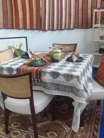 A beautifully set dining table, featuring a hand-block printed tablecloth, woven blinds, and artisanal ceramics.