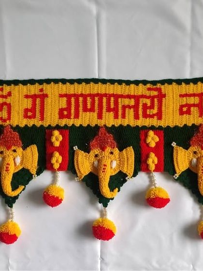 A full view of the classic Ganpati toran against a white background, showcasing the entire design with five Ganpati motifs and hanging pom-poms.