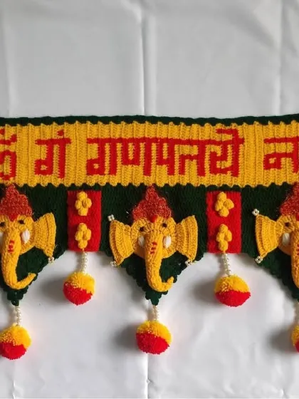 A full view of the classic Ganpati toran against a white background, showcasing the entire design with five Ganpati motifs and hanging pom-poms.