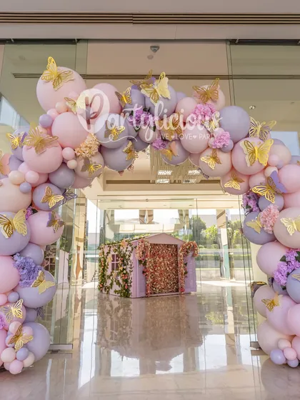 A grand entrance for a magical celebration. This full, pastel-colored balloon arch, adorned with golden butterflies, welcomed guests into a whimsical, fairytale-themed party.