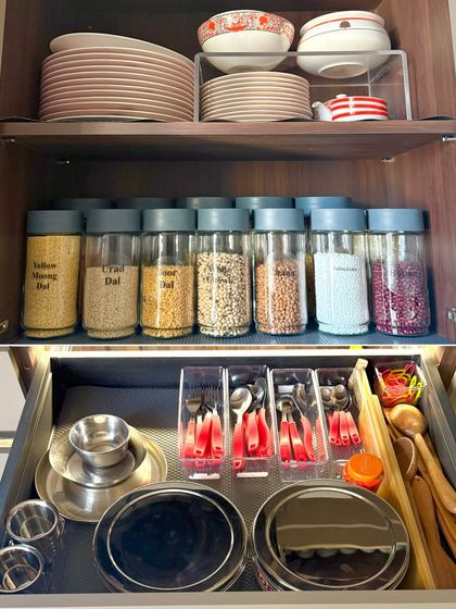 This image shows our integrated approach. A cabinet for dals and plates sits above a perfectly organized drawer for cutlery and everyday steel dishes.