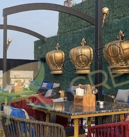 Another angle of the Lord of The Drinks project in Agra. This view shows our comfortable lounge seating with blue cushions, set against the custom green wall and decorative elements. It demonstrates how we can furnish a large, multi-zone outdoor space with different types of seating.