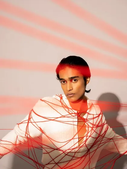 Another creative shot from the same editorial. The model's hair is styled neatly, and the skin is prepped to look flawless under the bright, projected light.