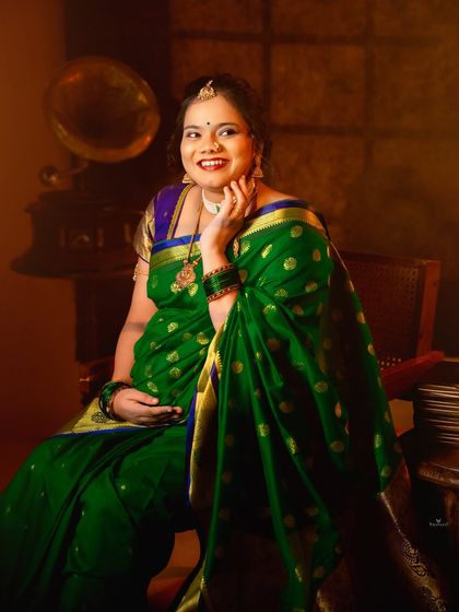 A close-up shot capturing the radiant smile of a mom-to-be. The rich colors of her green saree and the warm lighting create a joyful and inviting portrait.