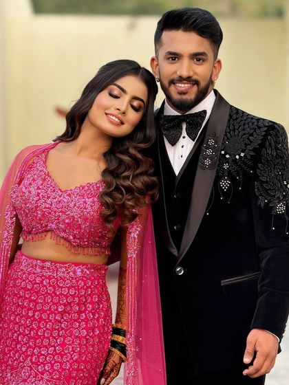A romantic portrait of a couple at their reception. The bride is wearing a vibrant pink lehenga, and her makeup is soft and glowing.