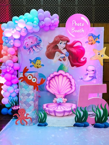 An underwater-themed photo booth for the mermaid party, complete with a clamshell seat, sea creature cutouts, and bubble-like balloons.