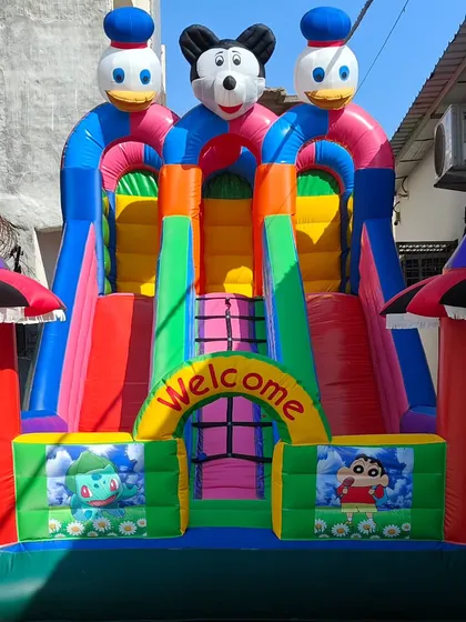 A vibrant 3-slider bouncy castle in a green and pink color scheme with Shinchan characters. The quality stitching and durable material are standard on all our products.