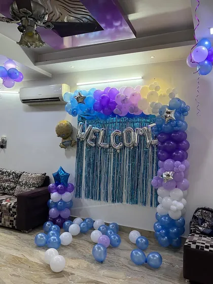 The full view of the 'Welcome' balloon backdrop with a foil curtain and balloon pillars.