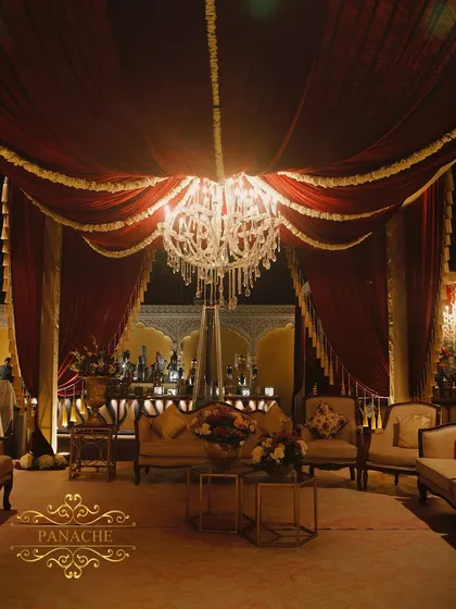 A cozy and regal seating arrangement under a draped canopy, with a well-lit bar in the background. We design these spaces to be both beautiful and functional for guest comfort.