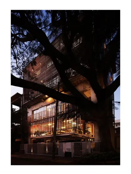 My own studio at dusk, conceived as a translucent lantern framed by a mature rain tree. The design is an honest expression of its structure, with three robust concrete portals supporting suspended galleries. It is a living example of my belief in open, evolving spaces that foster creativity.