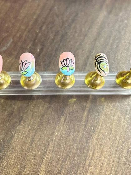 I love painting flowers, and this lotus design is one of my favorites. Here you can see the individual nails with hand-painted lotus and peacock feather details before they are assembled into a set.