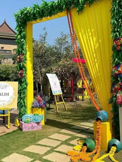 A cheerful and welcoming entrance for a Haldi function. The bright yellow arch, decorated with greenery and marigold garlands, sets a festive tone right from the start.