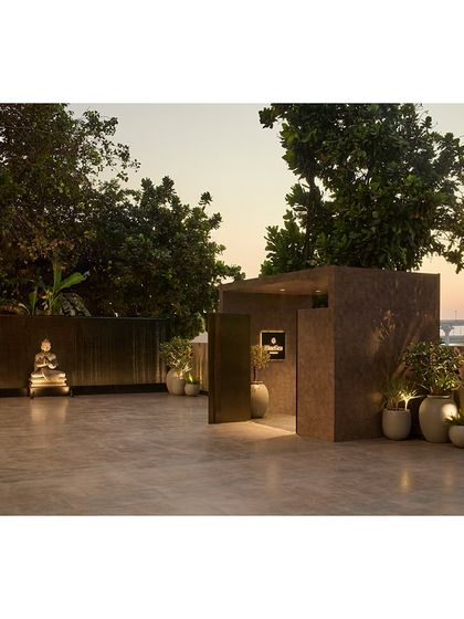 The outdoor patio of the Blue Sea Banquet at dusk. We redesigned the space with new paving and lighting, creating a serene pre-function area with views of the sea, centered around a calming Buddha statue.