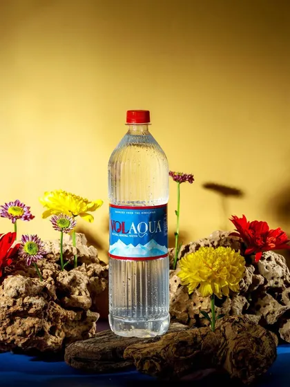 A creative concept for Volaqua, placing the bottle among fresh flowers. This image visually connects the water to nature and freshness, reinforcing its Himalayan origin story.