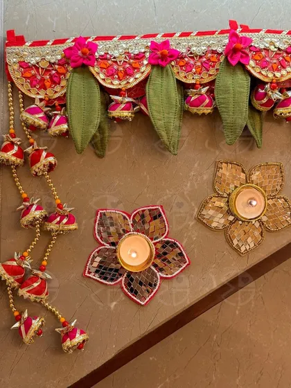 This bandhanwar features traditional leaf motifs and bell hangings. Paired with my flower-shaped mirror-work tea light holders, it creates a complete and charming decor set for your doorstep.