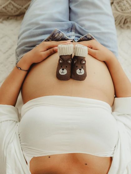 A sweet and playful detail shot. Placing tiny baby booties on the bump is an adorable way to symbolize the little feet that will soon be running around.