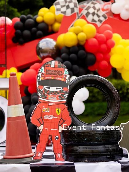 A cute cartoon racer cutout standing on a stack of tires, adding a playful touch to the Ferrari theme.