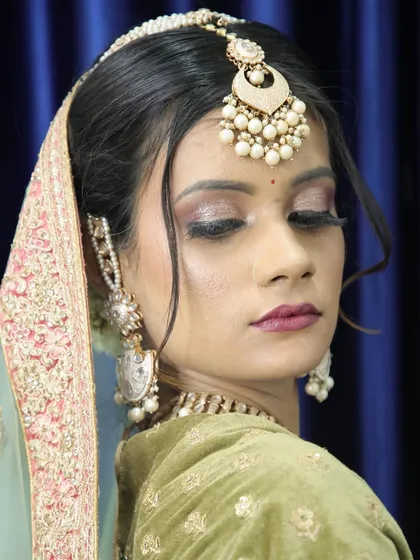 A close-up photo of a glamorous look with glittery eyes and a beautiful light green and pink lehenga.