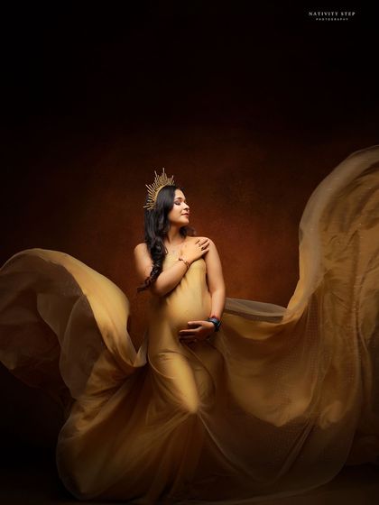 A graceful portrait in a golden gown, with the fabric flowing beautifully. The mother-to-be's serene expression and the added crown create a goddess-like image.