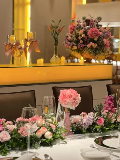 The tablescape featured a runner of delicate pink and purple flowers, with single pink peonies in minimalist vases. This created a soft, romantic atmosphere for the guests' dining experience.