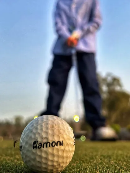 A creative close-up shot of a Hamoni-branded golf ball, with a golfer out of focus in the background.