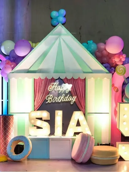 Welcome to Candyland. This delicious-looking stage features giant ice cream props, a candy-striped tent, and personalized marquee letters for a sweet-themed birthday.