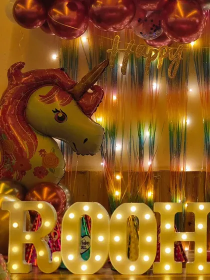 Close-up of the marquee letters and unicorn foil balloon from Roohika's first birthday party, highlighting the warm and magical lighting.