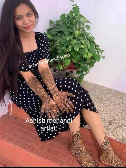 A happy client posing with her full hand and foot mehandi, a perfect look for any celebration.