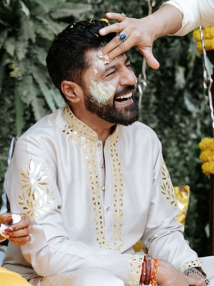 The groom's Haldi begins! A moment of pure laughter and tradition as the turmeric paste is applied, marking the start of the wedding rituals.