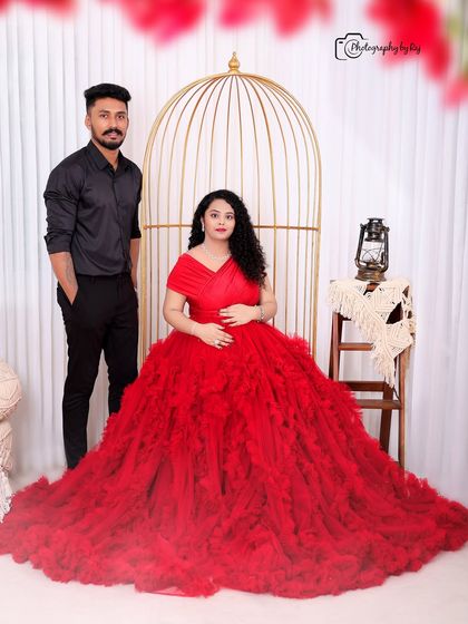 A romantic studio portrait of a couple in our bohemian setup. The mother-to-be is wearing a stunning red ruffled gown.