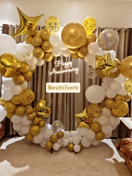 An elegant 50th anniversary celebration in classic gold and white. This decor includes a full balloon ring, a 'Happy Anniversary' neon sign, and star-shaped foil balloons, making the golden jubilee feel extra special and grand.