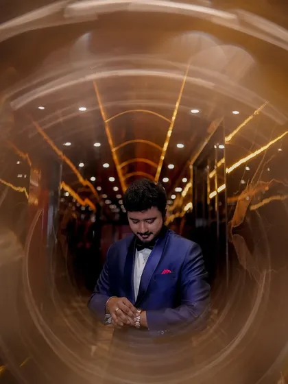 A creative portrait of the groom, looking dapper in his blue tuxedo. The unique circular light effect adds a stylish and modern touch to this Sangeet look.