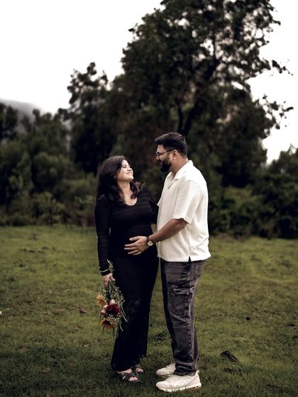 A lovely portrait of the couple standing together in a field, holding a bouquet of flowers. Their shared look is full of love and anticipation.