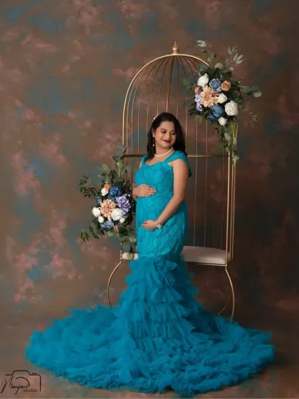 A portrait of a glowing queen. The mermaid-style teal gown looks stunning against the dark backdrop, and the cage prop adds a touch of regal elegance.