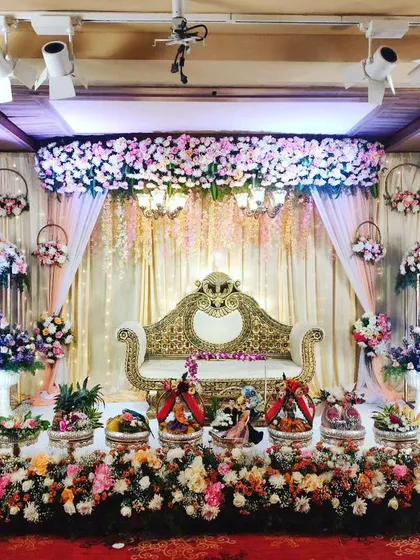A beautiful wedding reception stage filled with my decorative platters. The floral arrangements and hanging elements complement the ornate sofa and create a luxurious feel for the couple.