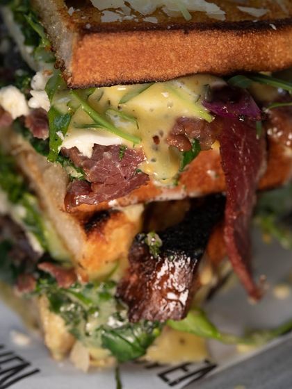 A super close-up of our stacked sandwich, showing the delicious layers of meat, cheese, sauce, and greens. It's a real sandwich.