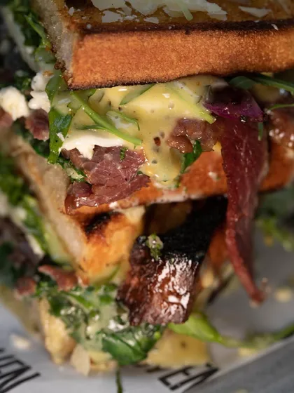 A super close-up of our stacked sandwich, showing the delicious layers of meat, cheese, sauce, and greens. It's a real sandwich.