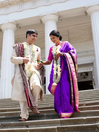 The couple descending the steps of the court, hand in hand. The bride looks effortlessly elegant in her traditional attire.