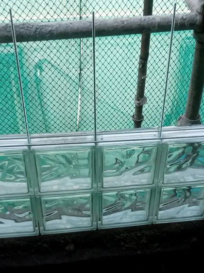 The meticulous installation of glass bricks for a staircase wall. Structural metal wires are carefully placed between each brick to ensure stability and a clean, finished look.