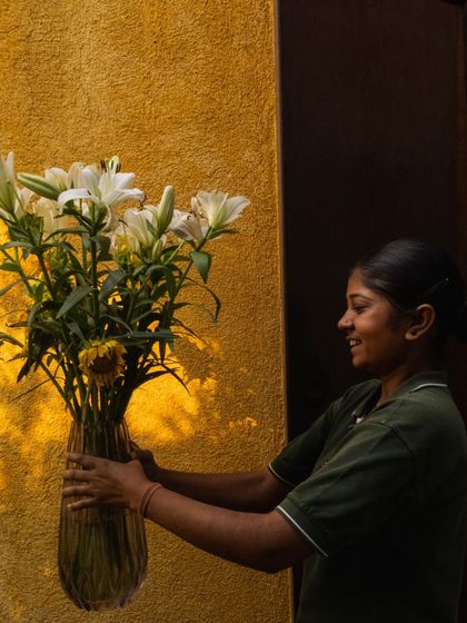 A smiling staff member holds a vase of fresh lilies, a small gesture that embodies the warm and welcoming spirit of Anvaya.
