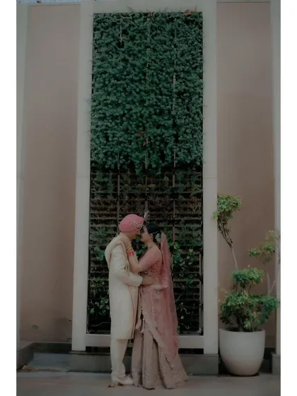 The couple shares an intimate moment in front of a green wall, their embrace full of warmth and affection.